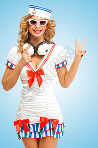 水手女孩位时尚的女水手戴着太阳镜的复古照片,她的脖子上戴着老式的音乐耳机,用手指蓝色背景上v号背景