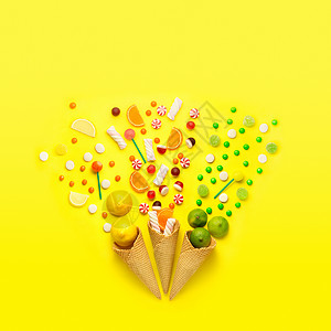 创造的静物照片三个华夫饼锥与糖果,水果棉花糖黄色背景图片