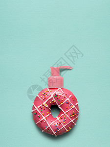 创意静物的美味甜甜甜圈与化妆品泵分配器蓝色背景图片