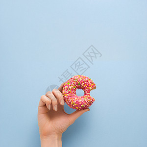 蓝色背景上手甜甜圈的创意照片图片