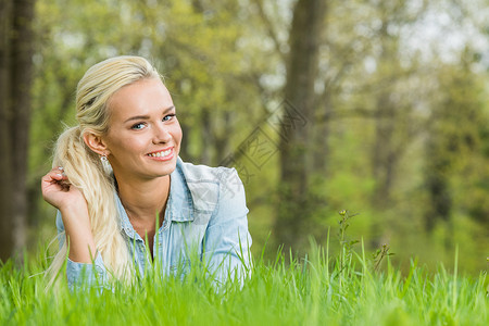 躺青草上的女人轻的金发女人躺春天公园的绿草地上图片
