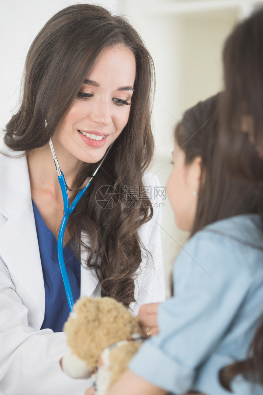 儿科医生女孩美丽的女儿科医生检查孩子与泰迪熊办公室图片