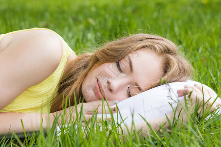 轻的女人睡清新的春草里的白色枕头上女人睡草地上图片