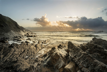 美丽的充满活力的日落英国康沃尔海岸的岩石海滩上图片