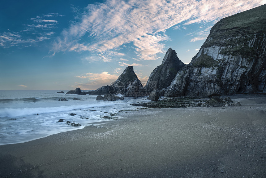 美丽的五颜六色的日落海滩景观与锯齿状的岩层图片
