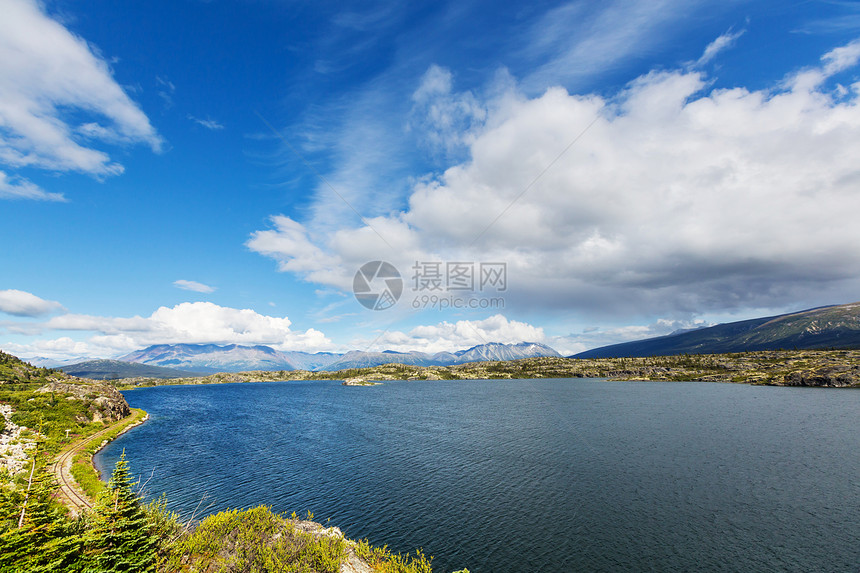 平静的景色加大的山湖旁边,岩石平静的水中反射图片