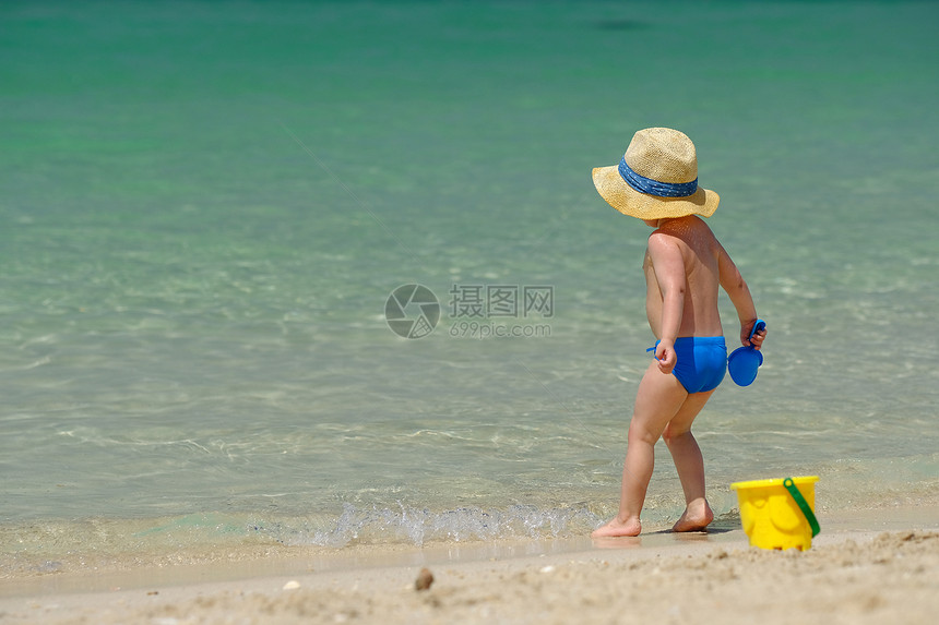 两岁的蹒跚学步的男孩海滩上玩海滩玩具图片