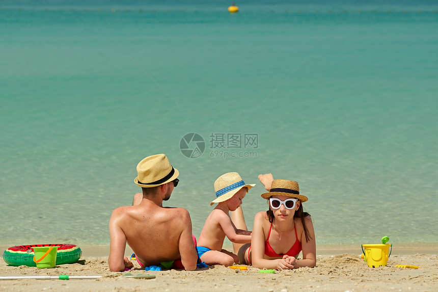 海滩上的家人两岁的蹒跚学步的男孩父母海滩上玩海滩玩具图片