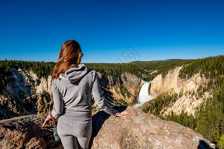 女子游客与相机俯瞰下瀑布瀑布黄石公园大峡谷,怀俄明州,美国图片