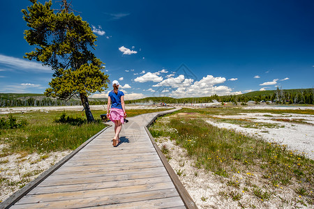 美国怀俄明州黑沙盆地黄石公园带相机徒步旅行的女游客图片