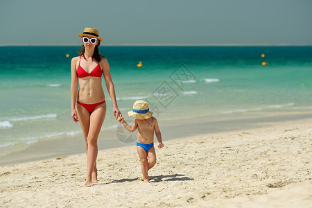 蹒跚学步的男孩妈妈海滩上散步两岁的蹒跚学步的男孩妈妈海滩上散步图片