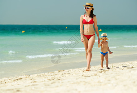 蹒跚学步的男孩妈妈海滩上散步两岁的蹒跚学步的男孩妈妈海滩上散步图片