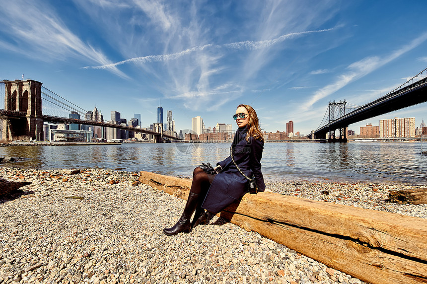纽约布鲁克林的女人女人坐纽约布鲁克林大桥曼哈顿大桥的海岸上图片