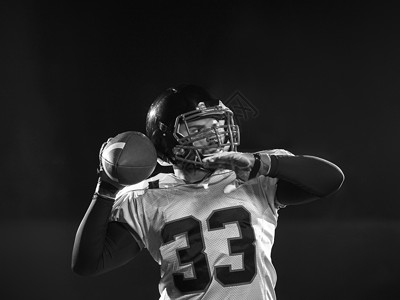 美国足球运动员黑色背景下投掷橄榄球图片