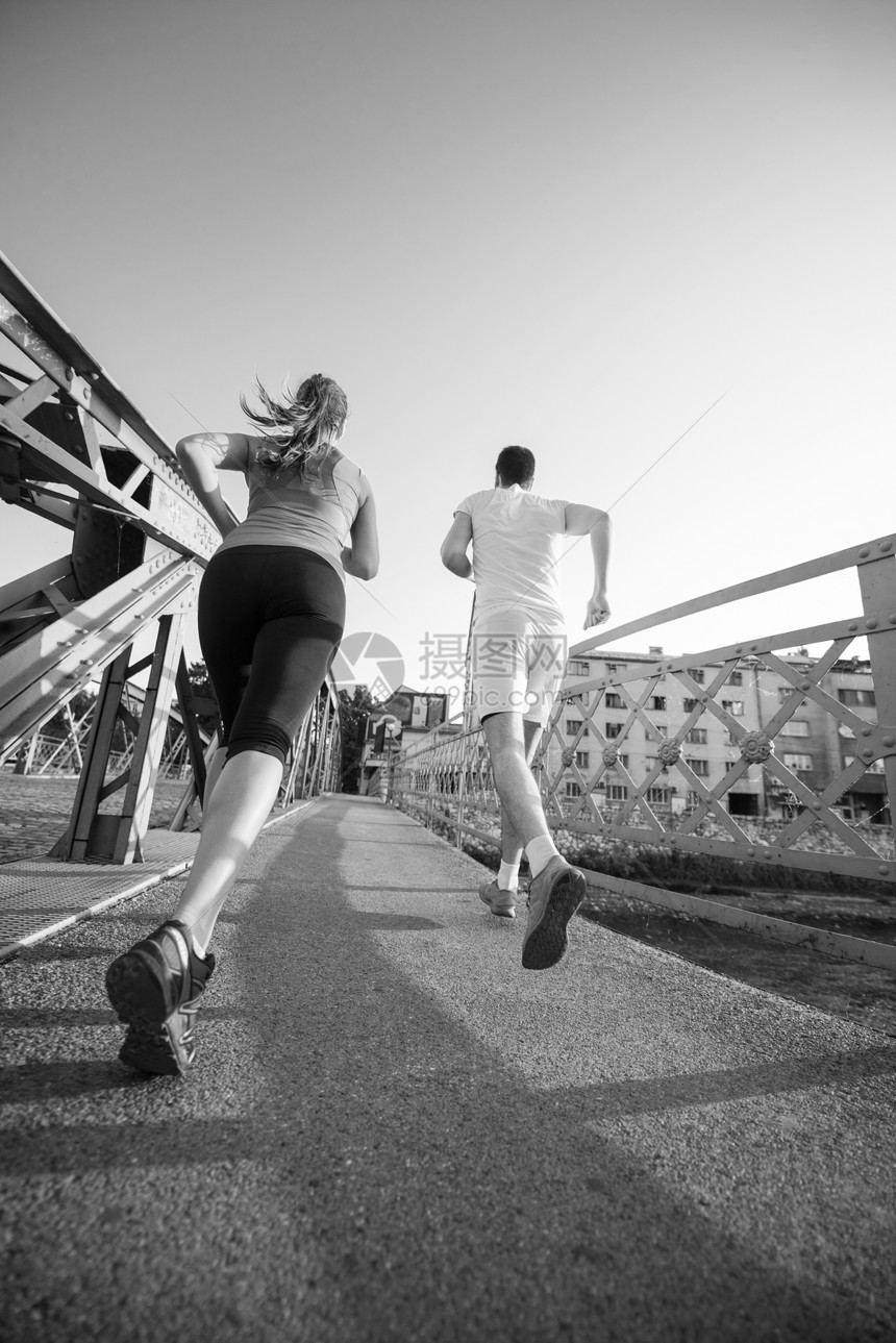 城市运动,健康的轻夫妇阳光明媚的早晨慢跑过桥图片