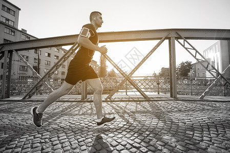 轻的运动男子慢跑过桥阳光明媚的早晨城市图片