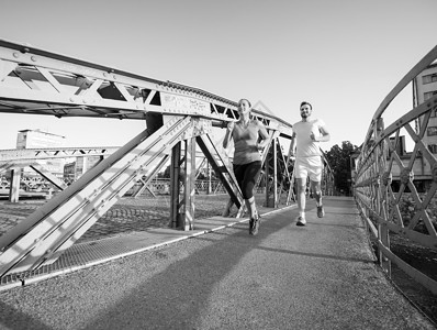 城市运动,健康的轻夫妇阳光明媚的早晨慢跑过桥图片