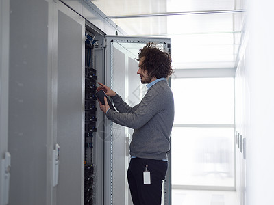 轻的IT技术人员大数据中心的服务器上用数字电缆分析仪背景图片