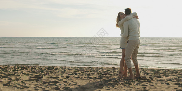 轻夫妇秋天阳光明媚的日子里海滩上玩得很开心背景图片
