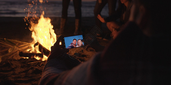 男孩海滩篝火旁给女孩看了张手机上的照片图片
