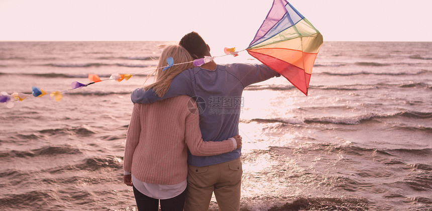 相爱的夫妇海滩上放风筝,秋天的日子里玩得很开心图片
