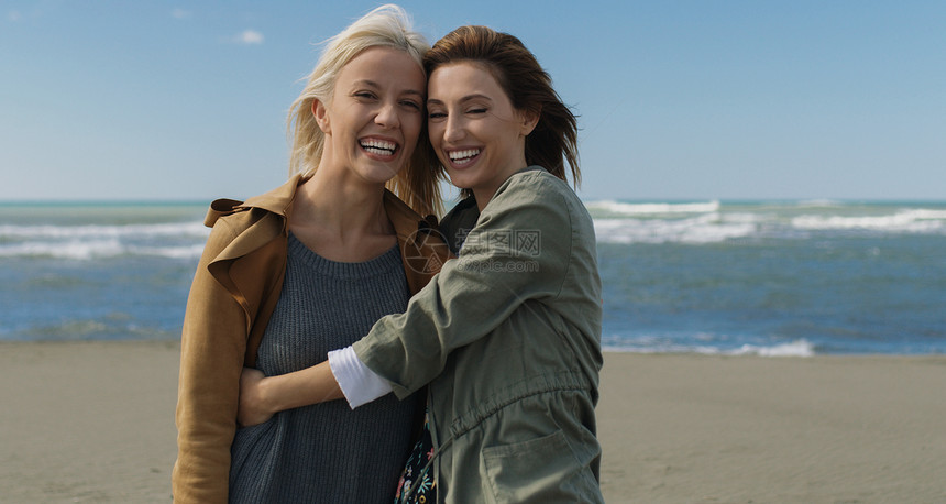 两个可爱的轻女人微笑着享受着秋天海洋上散步的生活图片