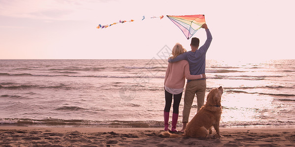 Autmun的天,夫妇海滩上跑步,用狗牵着手背景图片