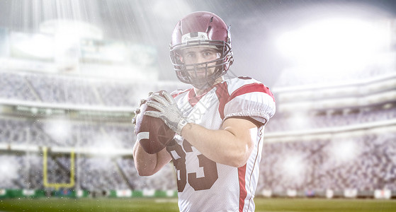 名四分卫美国足球运动员用灯光照明弹大型现代体育场上扔球背景图片