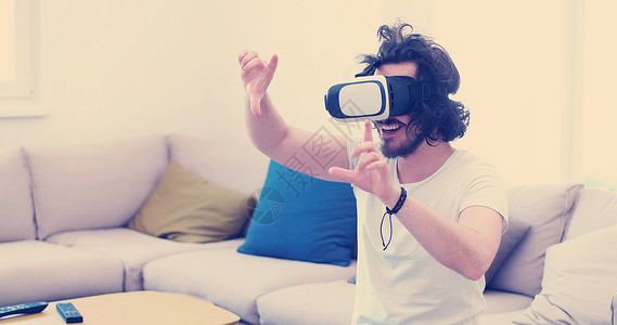 快乐的男人家里用虚拟现实的VR耳机眼镜获得体验图片