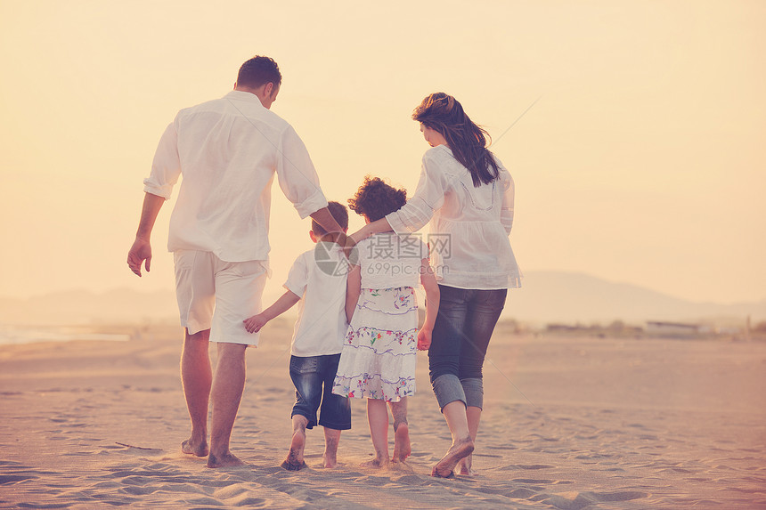 快乐的轻家庭海滩上玩,日落时跑步跳跃图片