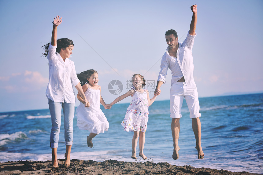 穿着白色衣服的幸福的轻家庭美丽的海滩度假时玩得很开心图片