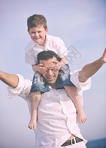 快乐的轻父亲儿子日落时享受海滩上的时光,代表着健康的家庭支持理念图片