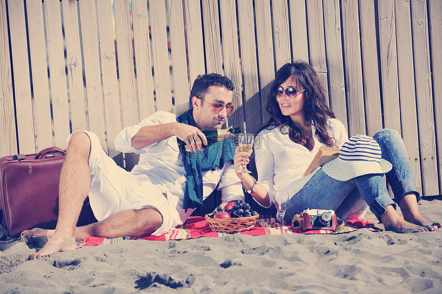 快乐的轻夫妇海滩上野餐,暑假玩得很开心图片