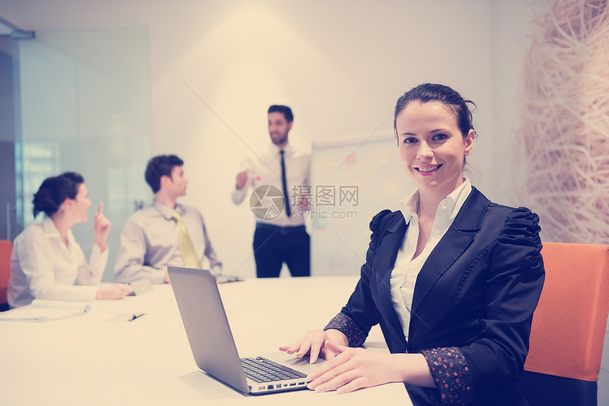 轻的商务女会见USINEG笔记本电脑,现代明亮的创业办公室内部背景的群人白色的翻板上笔记,并计划想法进行头脑风图片