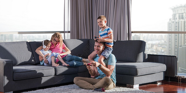 幸福的家庭爸爸妈妈孩子们玩电子游戏,爸爸儿子地板上玩电子游戏背景图片