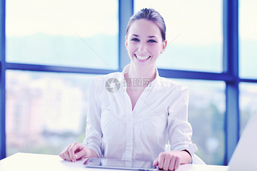 轻漂亮的商业女室内明亮的现代办公室的笔记本电脑上工作的肖像图片