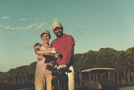 高尔夫球场上幸福轻夫妇的肖像高尔夫球场上夫妇的肖像图片
