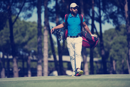 英俊的中东高尔夫球员背着包,球场上走下个洞高尔夫球手走路提包图片