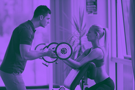轻的运动女与教练锻炼举重健身健身房双音轻的运动妇女与教练锻炼举重图片