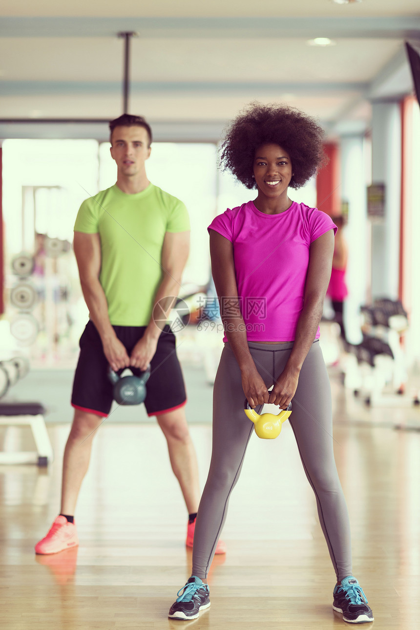 健康夫妇锻炼与举重交叉健身健身房,非裔美国妇女与阿夫罗发型两人交叉健身健身房锻炼体重图片