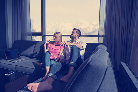 轻夫妇坐靠近窗户的沙发上,豪华的家里看电视轻的夫妇看电视图片