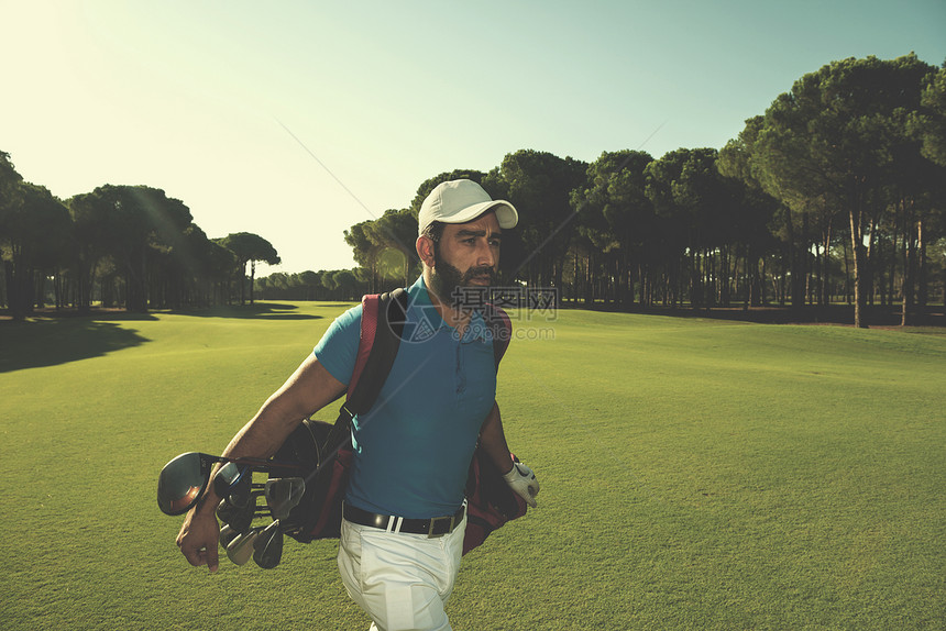 英俊的中东高尔夫球员携带袋子,并美丽的早晨日出时球场上行走高尔夫球手走路图片
