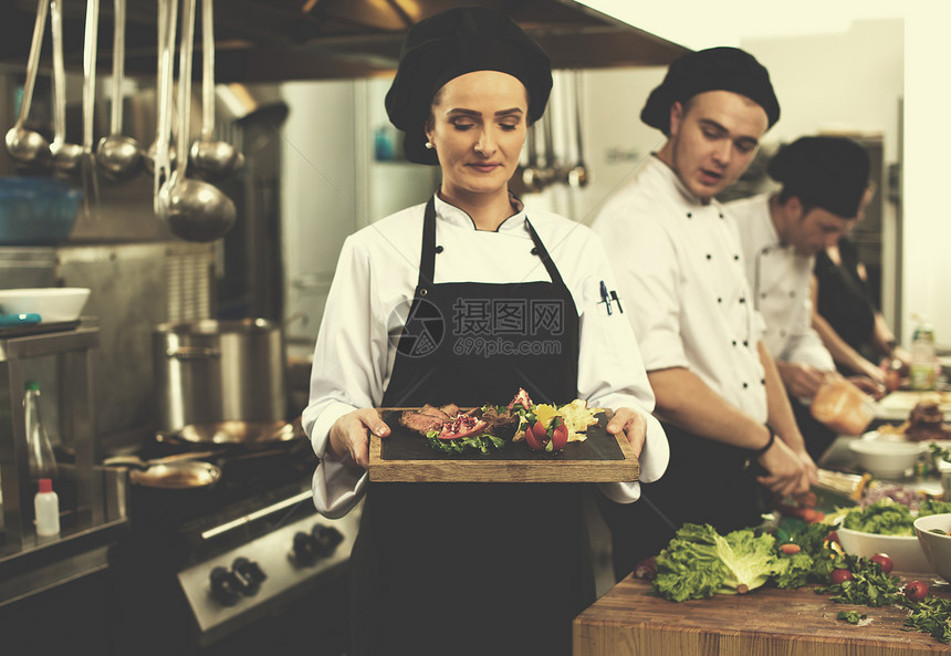 酒店餐厅厨房的女厨师着烤牛排盘蔬菜装饰女厨师着牛排盘图片