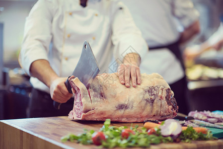 厨师餐厅厨房用斧头木板上切大块牛肉厨师切大块牛肉高清图片