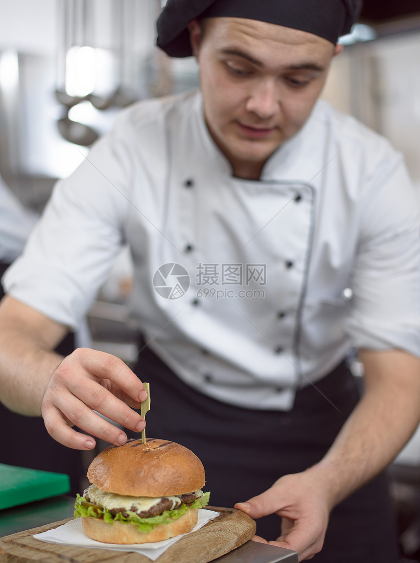 主厨把牙签放餐厅厨房的汉堡上厨师汉堡图片