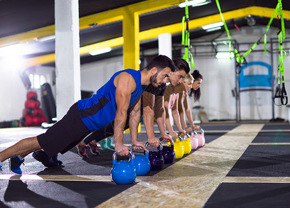 伏地魔群轻的健康运动员交叉健身健身房用水壶俯卧撑轻运动员用水壶俯卧撑背景