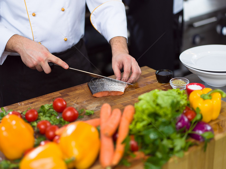 厨师手准备腌制鲑鱼鱼片,以便餐厅厨房煎炸厨师手准备腌制的鲑鱼鱼图片