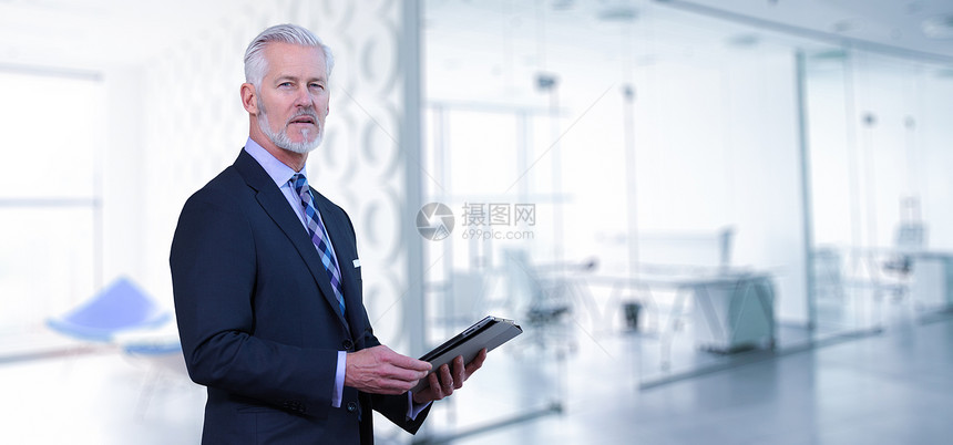 他办公室的高级商人他的现代办公室前用平板电脑的高级商人的肖像图片