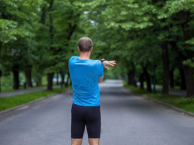 男跑步者早上训练前热身伸展健康的男跑步者早上训练前公园热身伸展图片