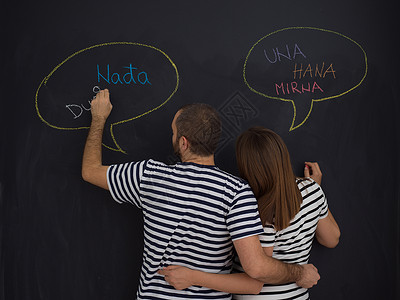 饼干写字框轻的怀孕夫妇想着他们未出生的孩子的名字,并把它们写黑板上怀孕的夫妇黑板上写字背景
